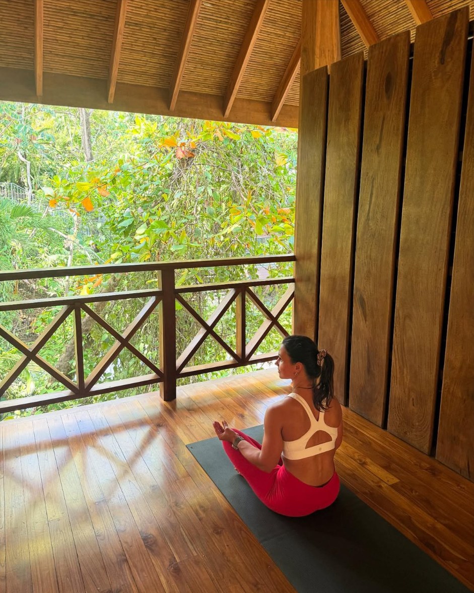 Nicole meditating on an open-air wooden deck at Bodhi Tree Yoga Resort during a previous visit