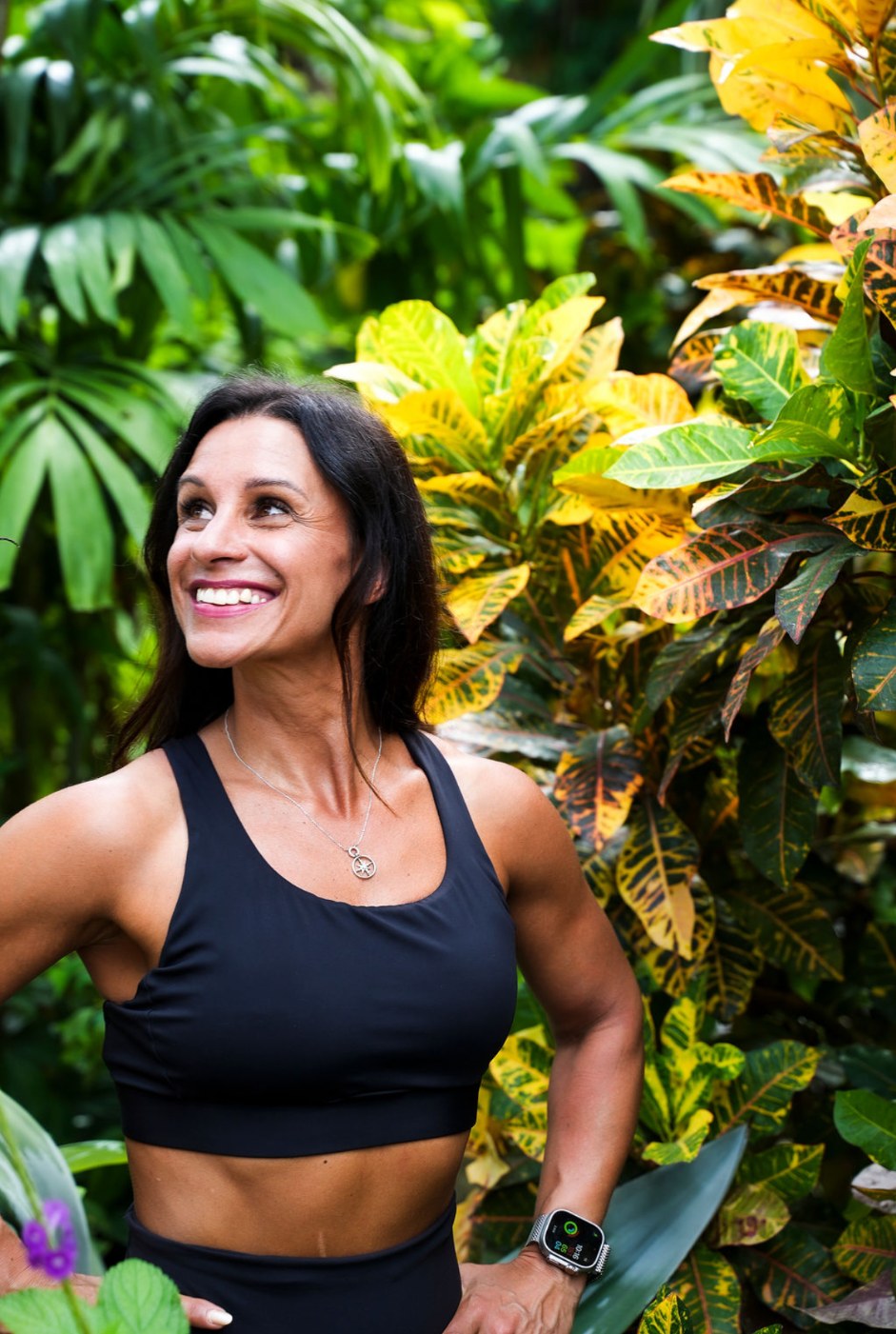 Nicole smiling among lush green and golden leaves